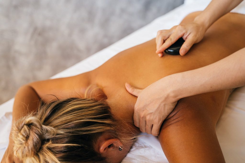 A Person Massaging a Client with a Hot Stone Massage Technique